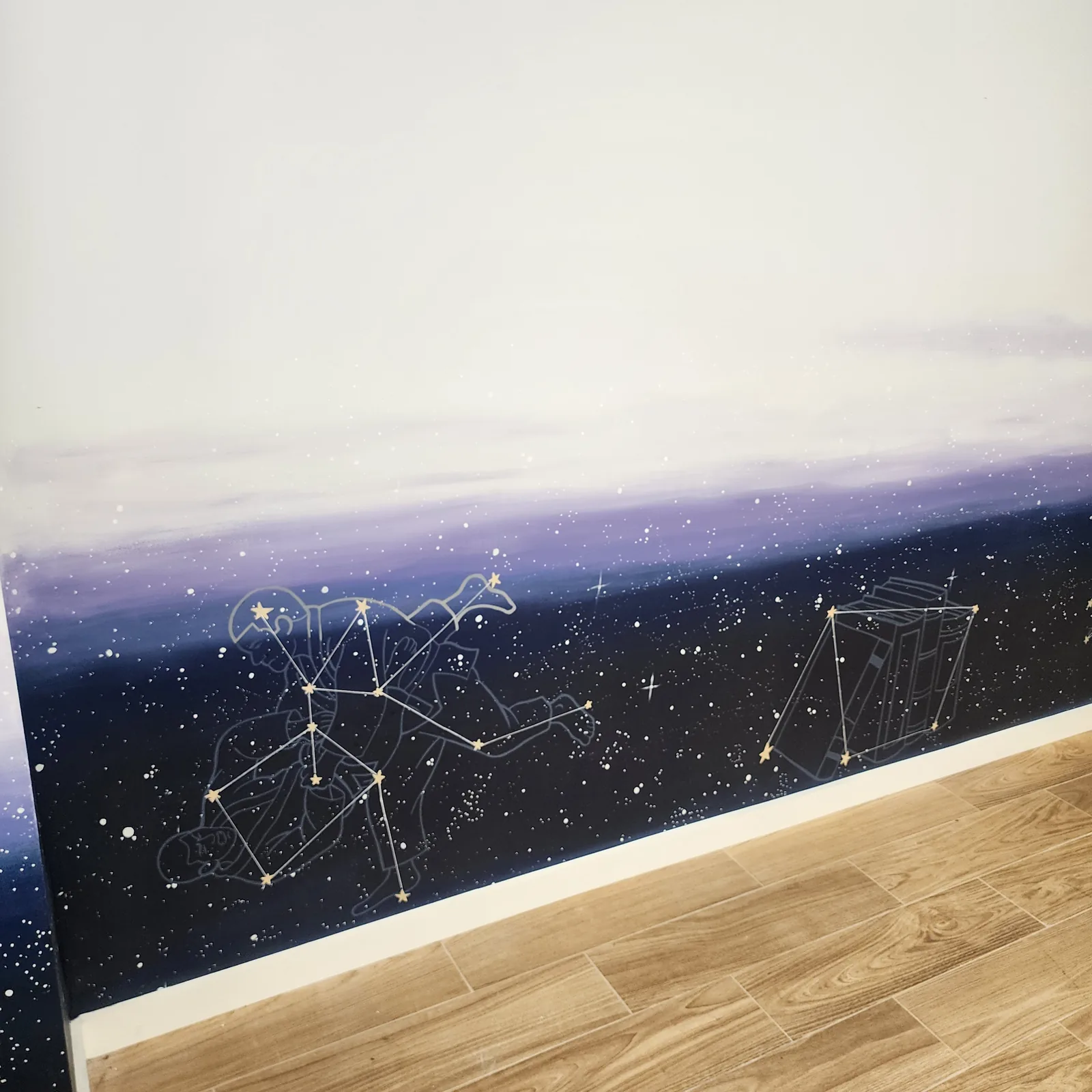 Close view of the night-sky mural: a constellation of figures reading together beside a constellation of books