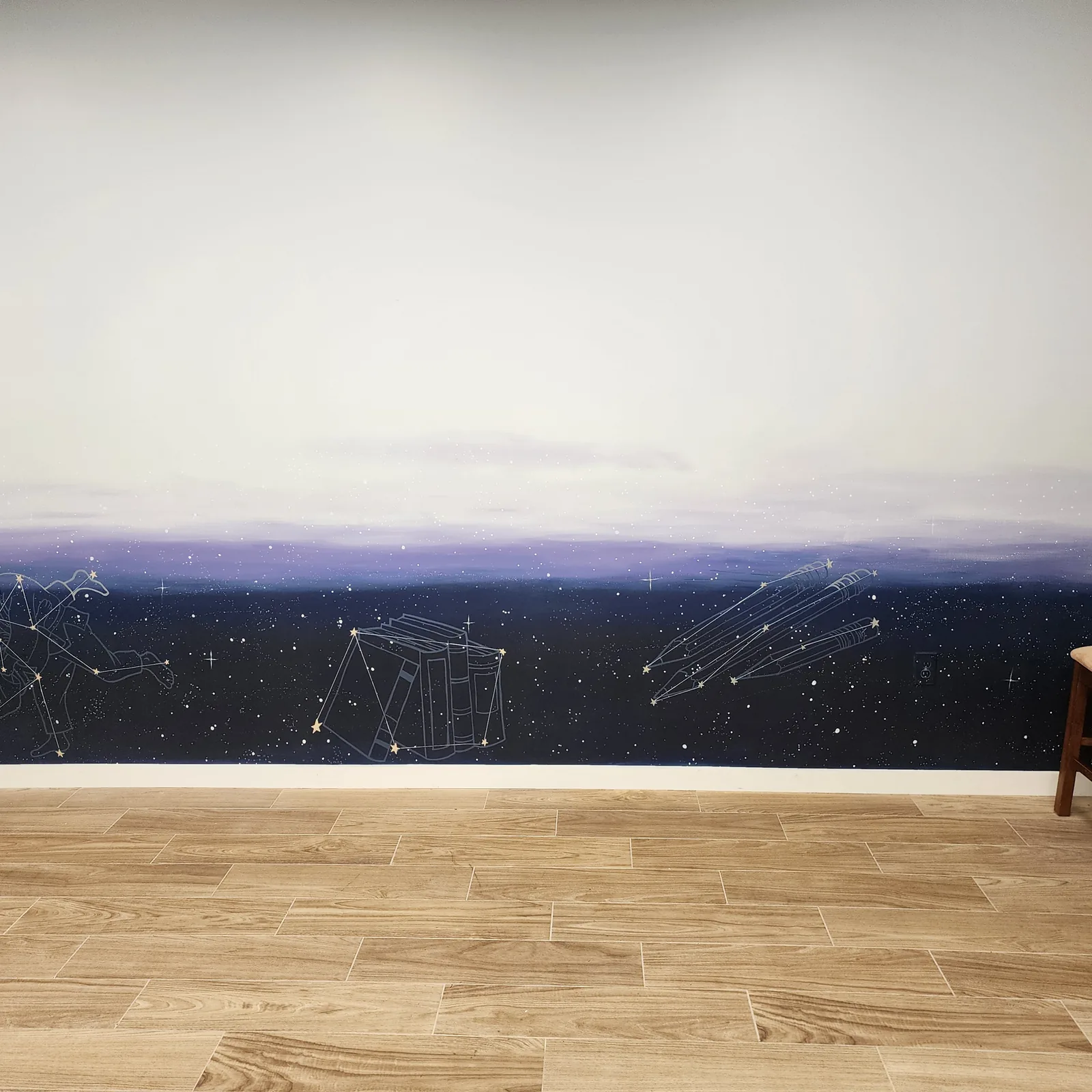 Night-sky mural fading from white to deep blue, with constellations drawn as a stack of books and a bundle of pencils